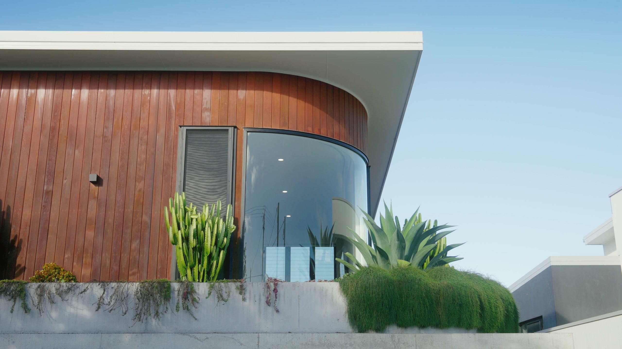 Full-width view of SCORPIO’s curved glazing, timber facade and landscaped frontage